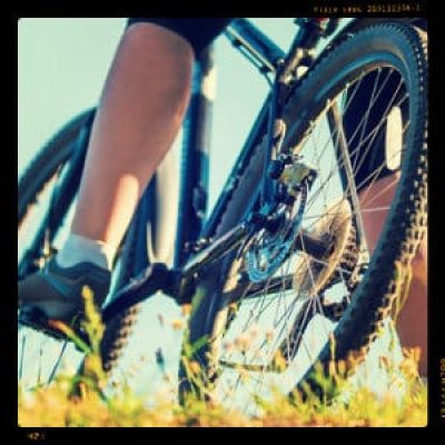 person standing with their bike - foot on the pedal