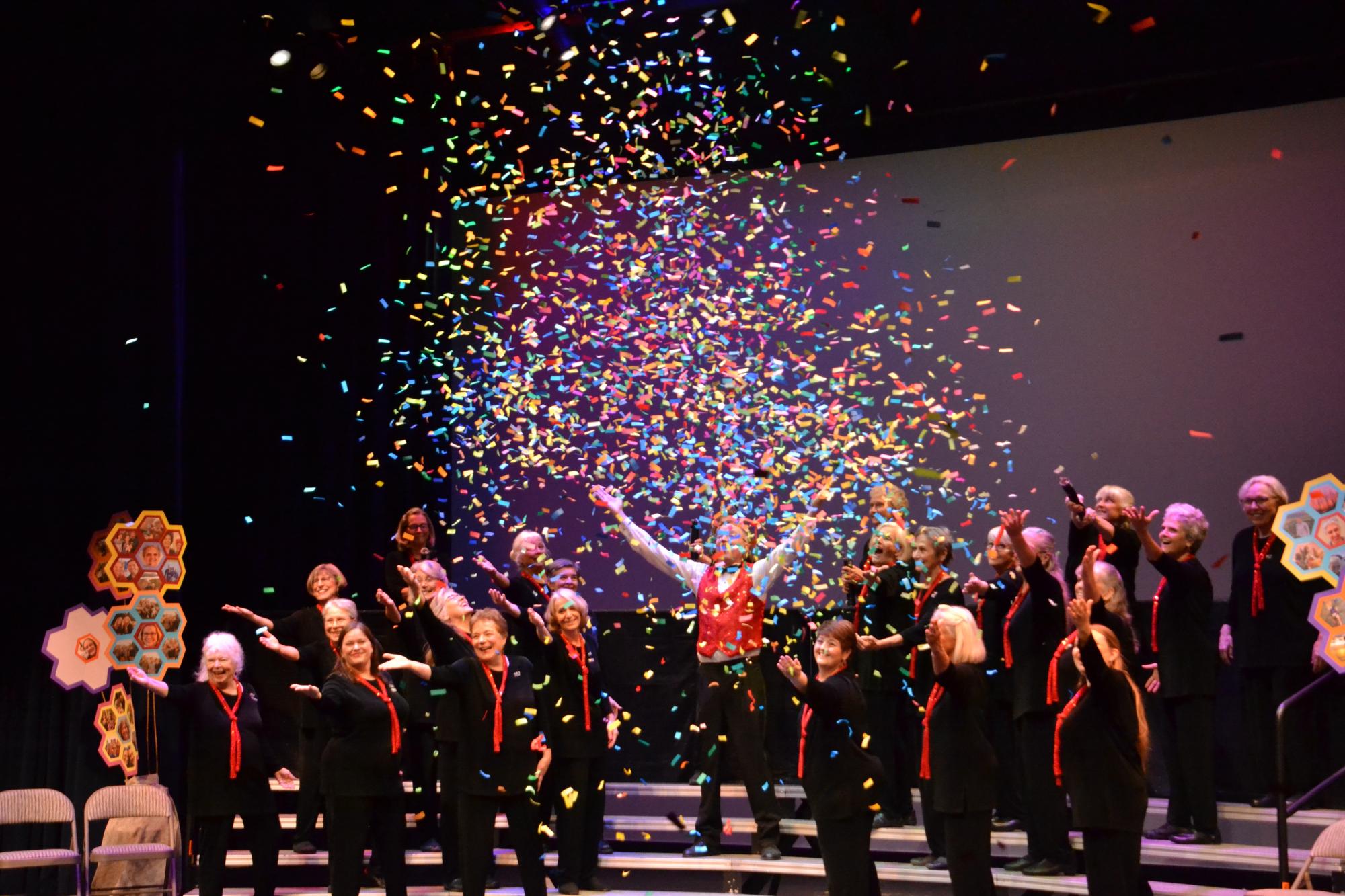 swifthouseinn_hotel_middlebury_musiccanchangetheworld Group of performers on stage cheering with colorful confetti raining down in celebration of a show.